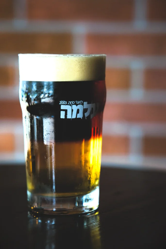 Слоистое пиво в бокале в пабе Beer Time в Ришон-ле-Ционе на фоне кирпичной стены.