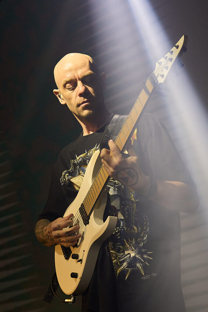 Галерея 24 Concert photographer Israel — bald tattooed guitarist playing white electric guitar under stage spotlight with smoke, live music performance photography, Boris Izmaylov Photography
